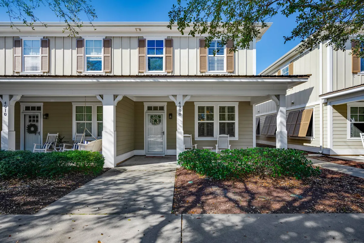 The exterior shot showcases a welcoming front porch with rocking chairs, a neatly landscaped entry, and a bright, inviting doorway. The scene hints at a comfortable transition from outdoor activities to home relaxation.