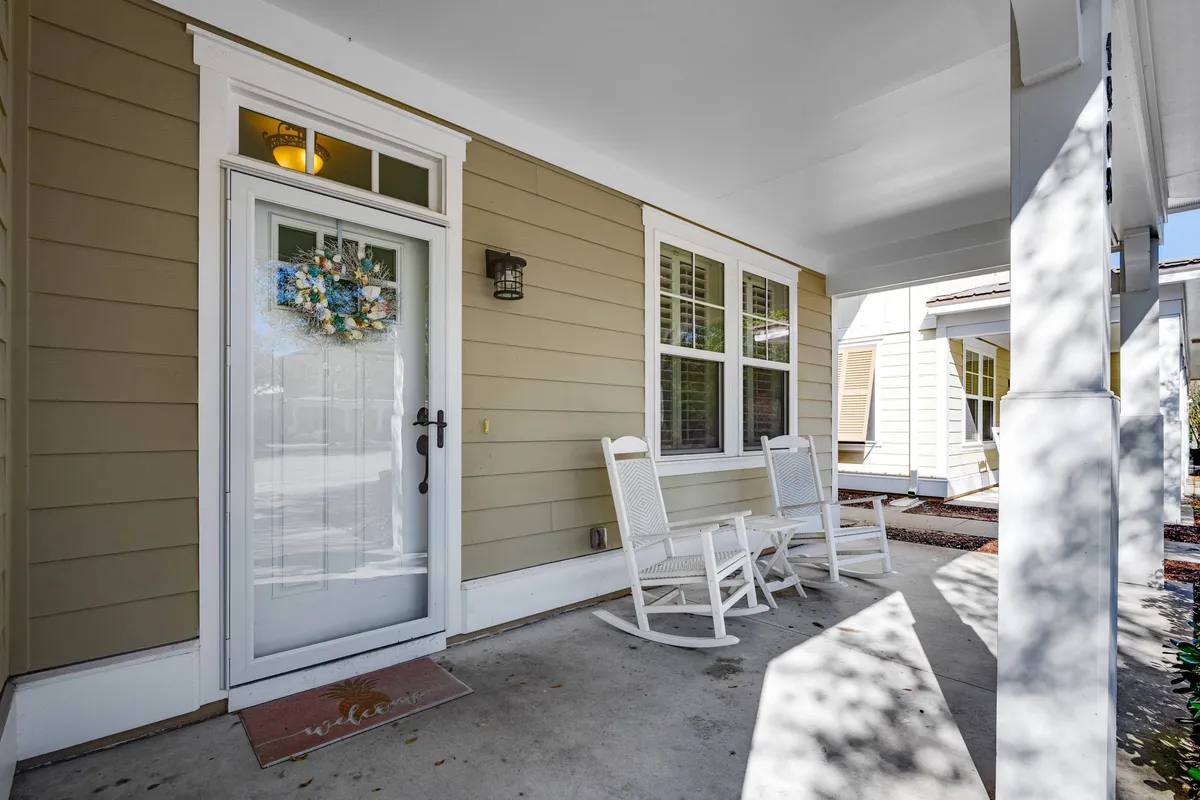 A cozy exterior view featuring a front door adorned with a seasonal wreath, rocking chairs, and warm porch lighting. The scene exudes a tranquil, welcoming atmosphere ideal for relaxing before or after wellness activities.