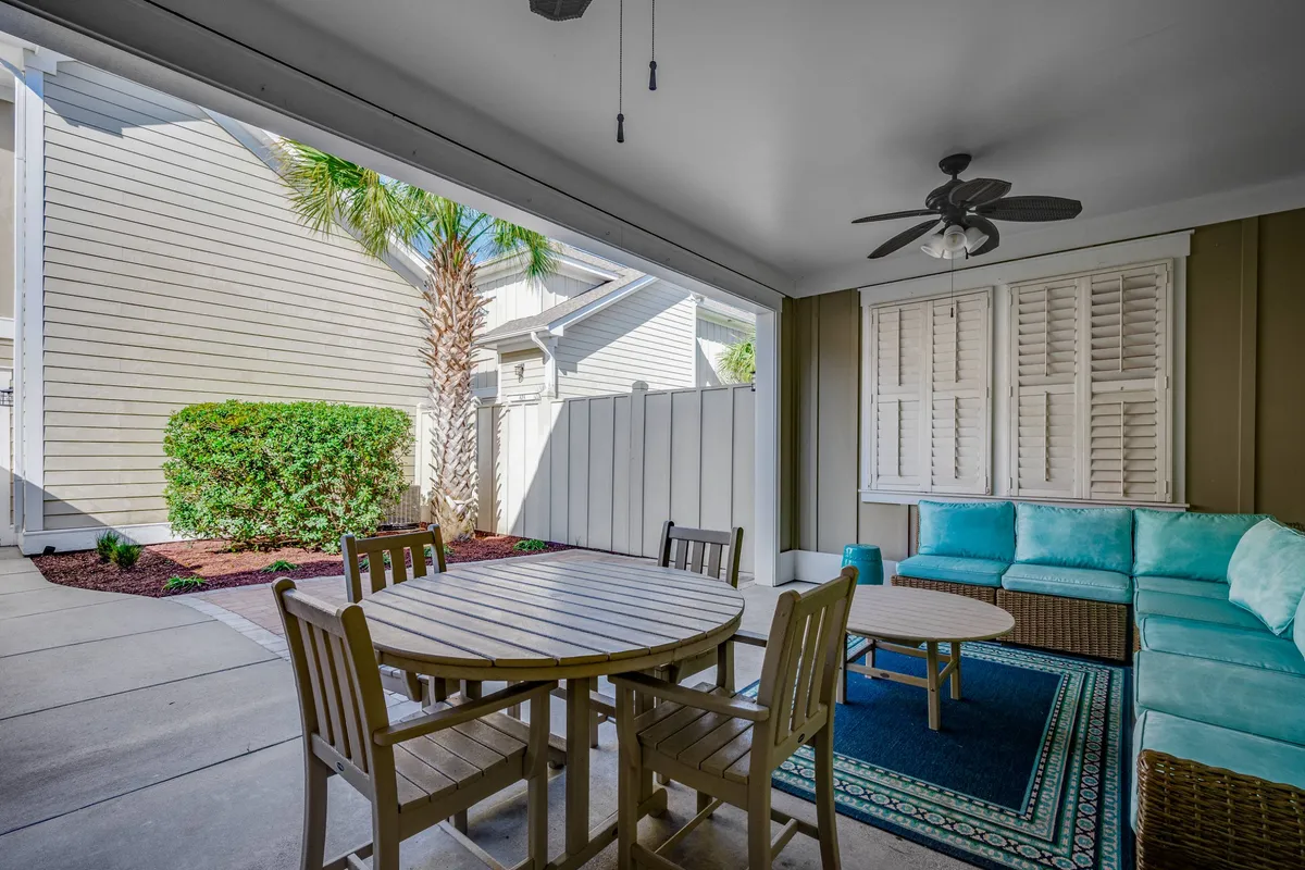 A welcoming dining area with a table set up near a sofa, complemented by a decorative rug and a tall potted palm tree, suggesting a space that opens to the outdoors. The soft ambient lighting and relaxed setup evoke a sense of comfort and togetherness, ideal for quiet morning coffee or intimate evening conversations.