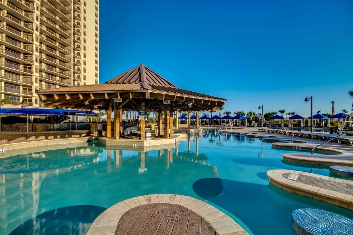 This exterior image features a resort swimming pool surrounded by a poolside gazebo, lounge chairs, and a tall building in the background. The scene is lively yet leisurely, with spaces for swimming, sunbathing, and socializing, capturing the essence of family relaxation after a day of activities.