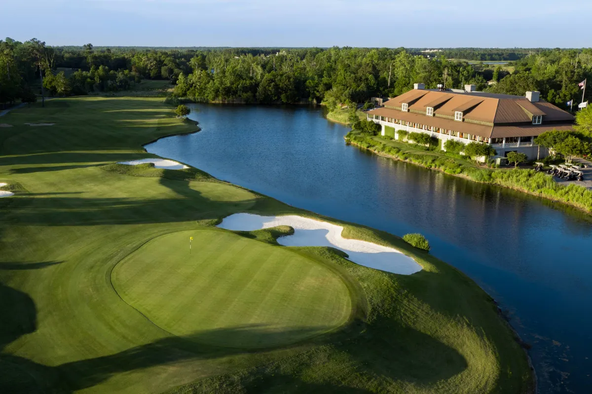 This exterior image captures a scenic golf course with a water body, sand traps, and the clubhouse in the background. The well-manicured greens and open skies evoke a sense of relaxation and recreation.
